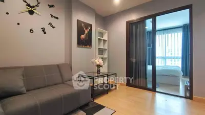 Modern living room with stylish decor and view into cozy bedroom through sliding glass door.