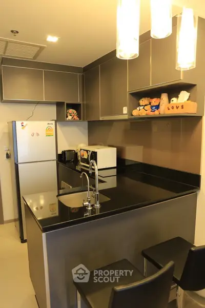 Modern kitchen with sleek black countertops and stylish lighting in a cozy apartment.
