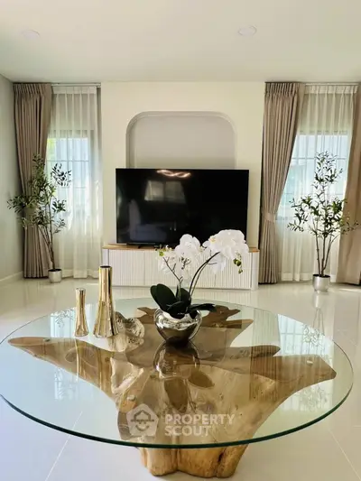 Elegant living room with modern decor and large TV, featuring a unique glass coffee table.