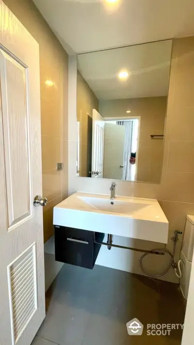 Modern bathroom with sleek sink and large mirror in contemporary apartment.