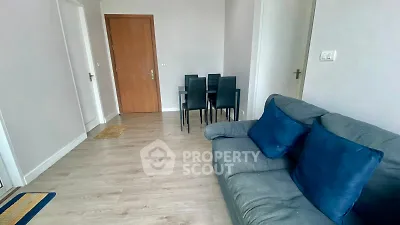 Modern living room with cozy sofa and dining area, featuring sleek wooden flooring and minimalist decor.