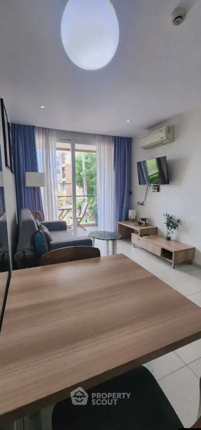Modern living room with balcony access, featuring stylish furniture and natural light.