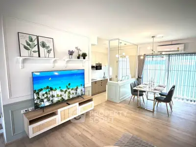 Modern living room with open kitchen and dining area, featuring stylish decor and natural light.