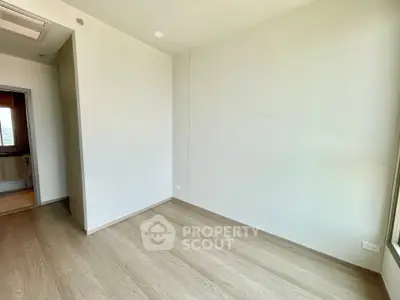 Spacious empty room with wooden flooring and large window, perfect for customization.