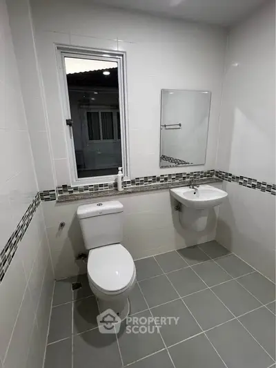 Modern bathroom with sleek fixtures and tiled walls, featuring a window for natural light.