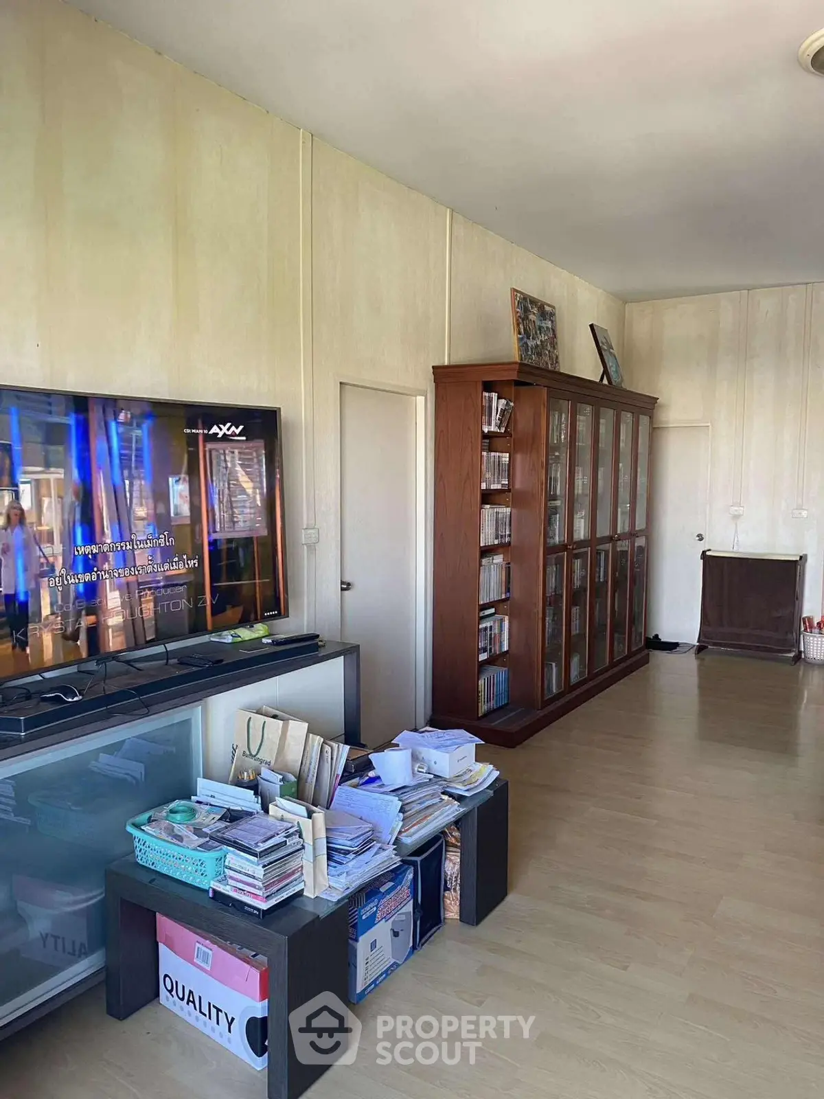 Spacious living room with wooden flooring and large bookshelf, perfect for relaxation and entertainment.
