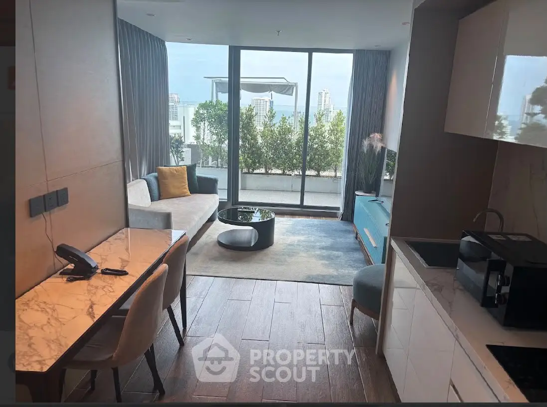 Modern living room with large windows and balcony offering stunning city views.