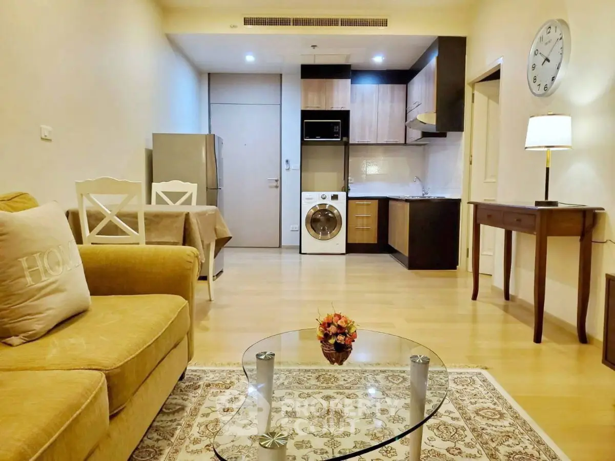 Cozy living room with modern kitchen, featuring washing machine and stylish decor.