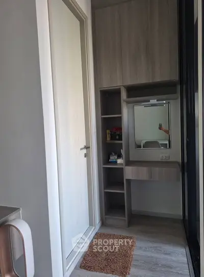 Modern compact storage area with built-in shelves and mirror in a stylish apartment.