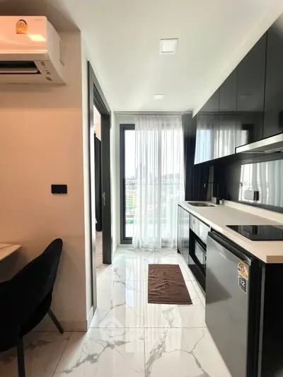Modern kitchen with sleek black cabinets and marble flooring in a high-rise apartment.