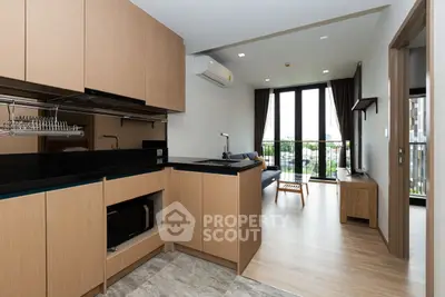 Modern open-layout kitchen with sleek cabinets leading to a bright living area with balcony view.