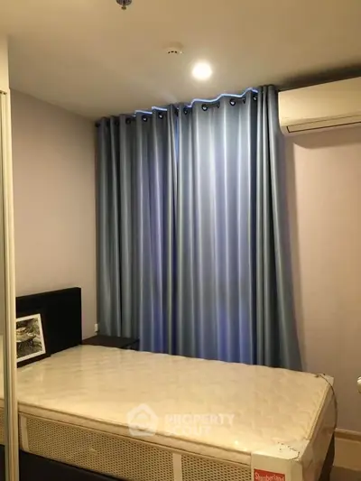 Cozy bedroom with blue curtains and air conditioning, perfect for restful nights.