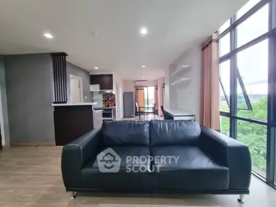 Spacious modern living room with large windows and stylish black sofa