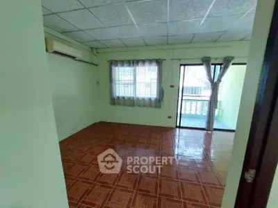 Spacious living room with tiled floor and balcony access in a cozy home.