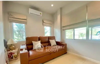 Cozy living room with brown leather sofa and large windows