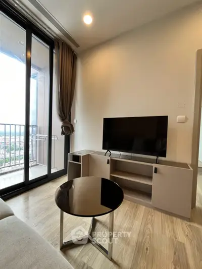 Modern living room with sleek TV stand and large glass doors leading to balcony with scenic view.