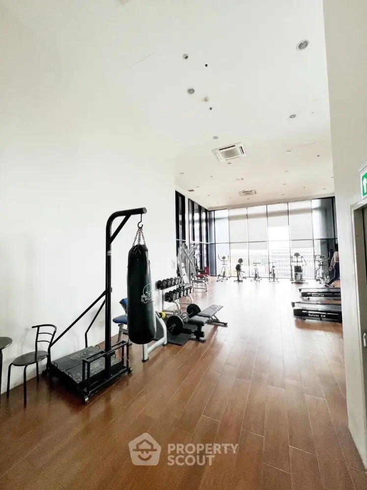 Spacious modern gym with large windows and fitness equipment in a luxury apartment building.