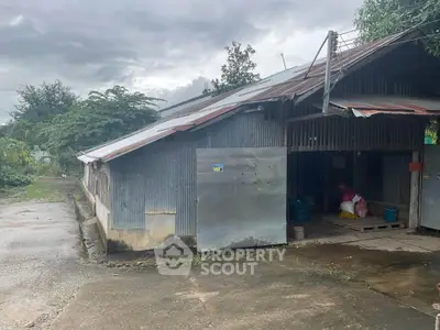 Rustic metal-roofed building with lush greenery, ideal for storage or agricultural use.