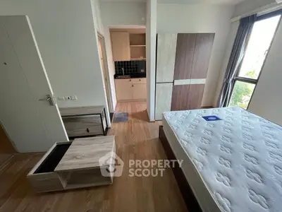 Modern bedroom with wooden flooring and compact kitchen area