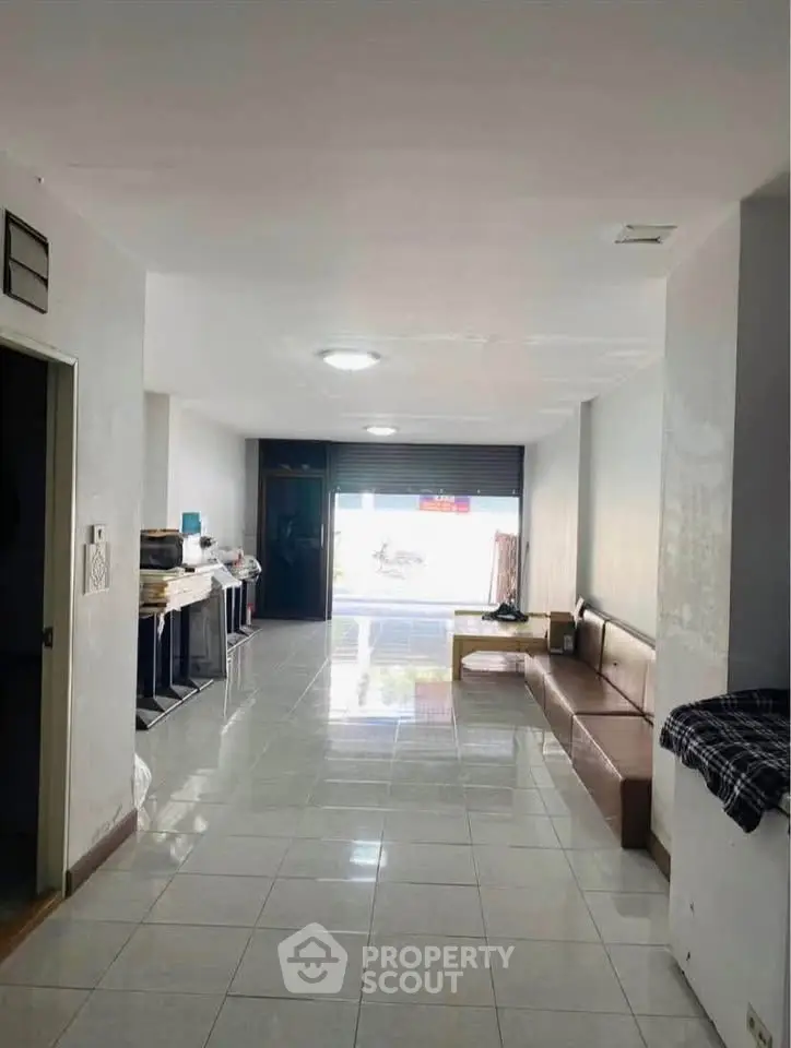 Spacious open-plan living area with tiled flooring and ample natural light, ideal for versatile use.