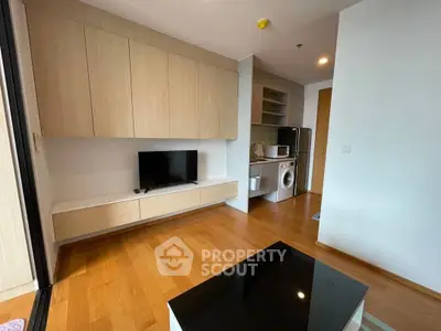 Modern living room with built-in TV unit and compact kitchen appliances.