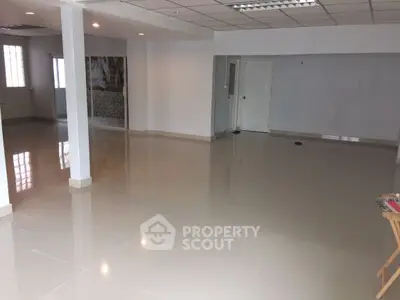 Spacious open-plan interior with glossy tiled floors and modern lighting.