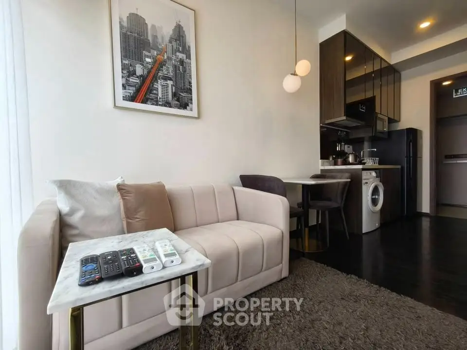 Modern living room with stylish decor, featuring a cozy sofa, chic dining area, and compact kitchen with appliances.