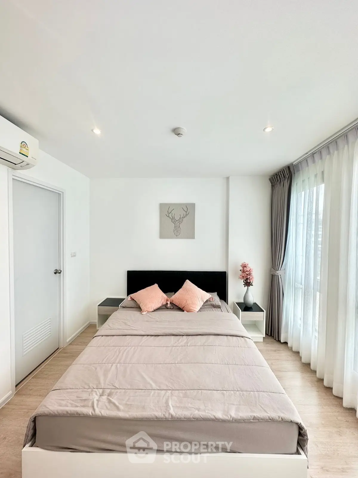 Modern bedroom with large windows and stylish decor in a bright apartment.