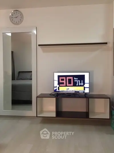 Modern living room with sleek TV stand and wall-mounted shelf, featuring a large mirror and minimalist decor.