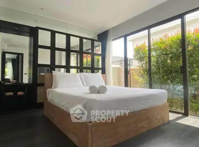 Modern bedroom with large windows and garden view, featuring a stylish bed and mirrored wardrobe.