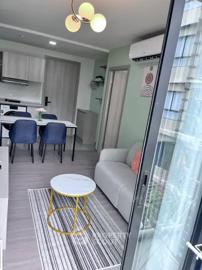 Modern open-plan living room with stylish furniture and kitchen area, featuring a cozy sofa and dining table.