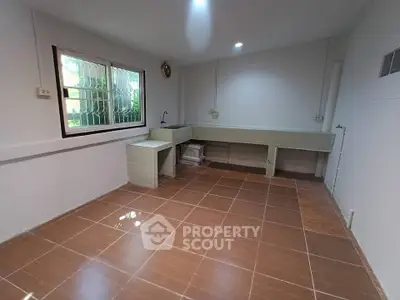 Spacious kitchen with tiled floor and large window, ideal for culinary creativity.
