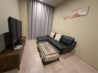 Modern living room with sleek black sofa and large TV, perfect for relaxation.