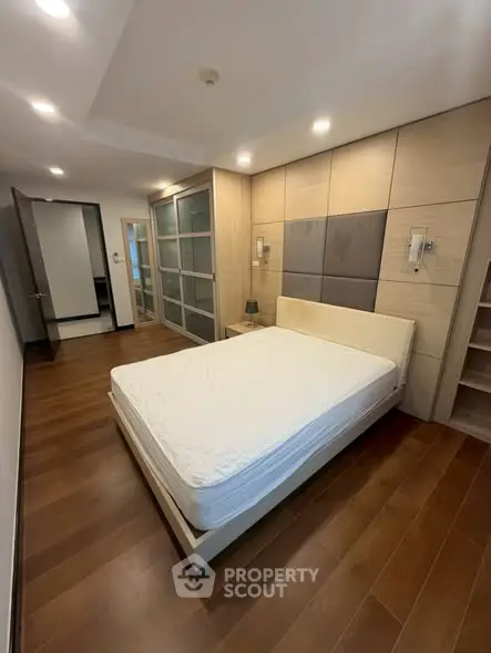 Spacious modern bedroom with wooden flooring and stylish lighting