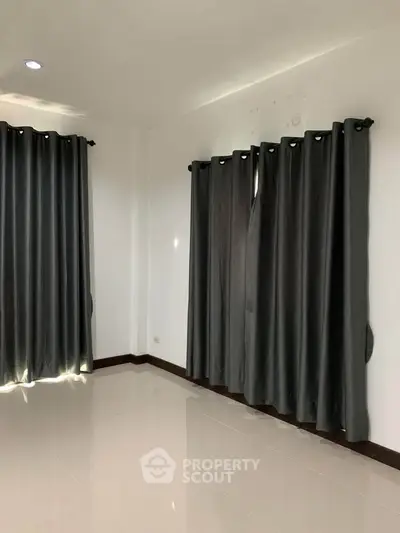 Spacious empty room with glossy tiled floor and elegant dark curtains, perfect for customization.