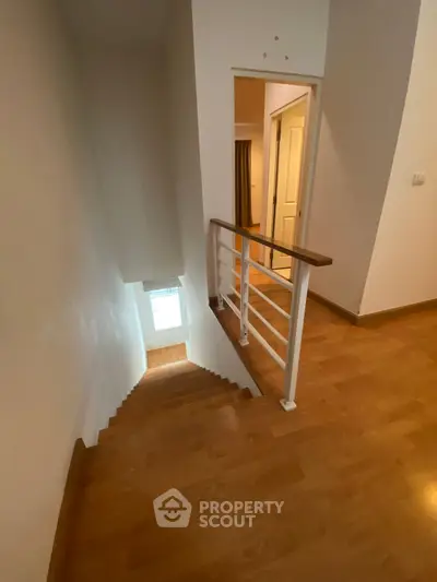 Spacious interior stairway with wooden flooring and modern railing design.