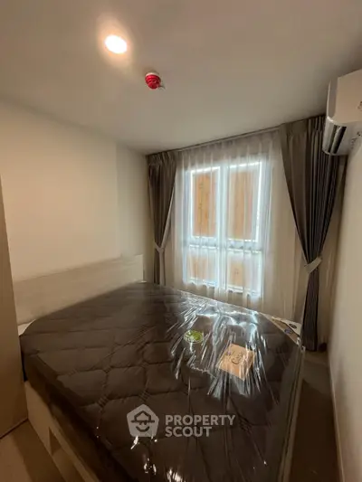 Cozy bedroom with large window and modern furnishings in a stylish apartment.