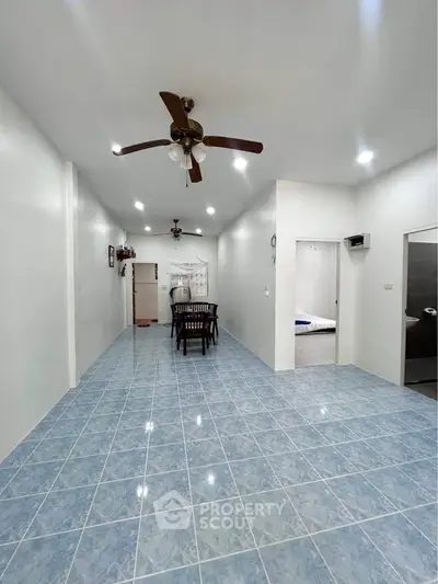 Spacious open-plan living area with ceiling fans and tiled flooring