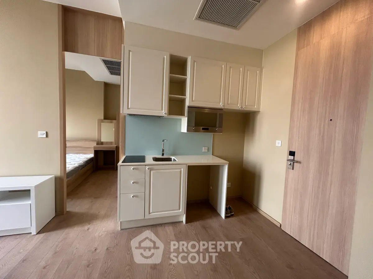 Modern compact kitchen with sleek cabinetry and wooden flooring in a cozy apartment.