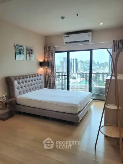 Spacious bedroom with city view and modern decor in high-rise apartment.