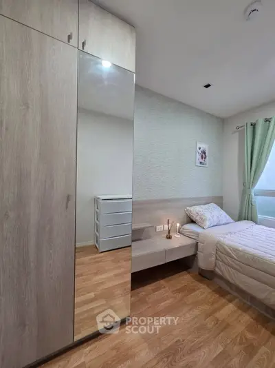 Modern bedroom with wooden flooring, mirrored wardrobe, and cozy bed setup.