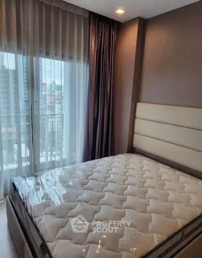 Modern bedroom with large window and city view, featuring a comfortable bed and elegant curtains.