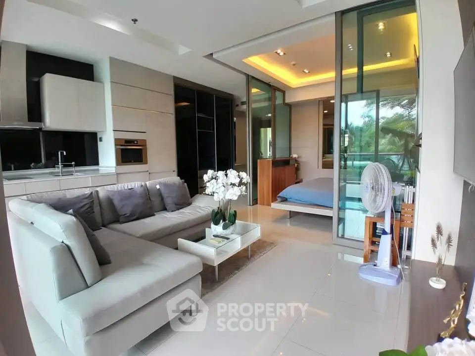 Modern open-plan living room with sleek kitchen and cozy bedroom view