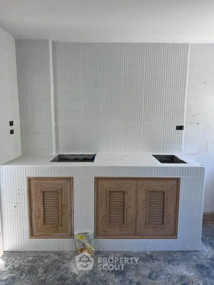 Modern kitchen under construction with sleek white tiles and wooden cabinets