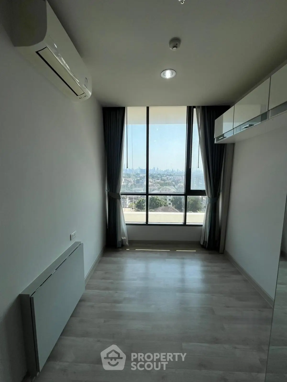 Bright room with large window offering stunning city view, modern air conditioning, and sleek flooring.