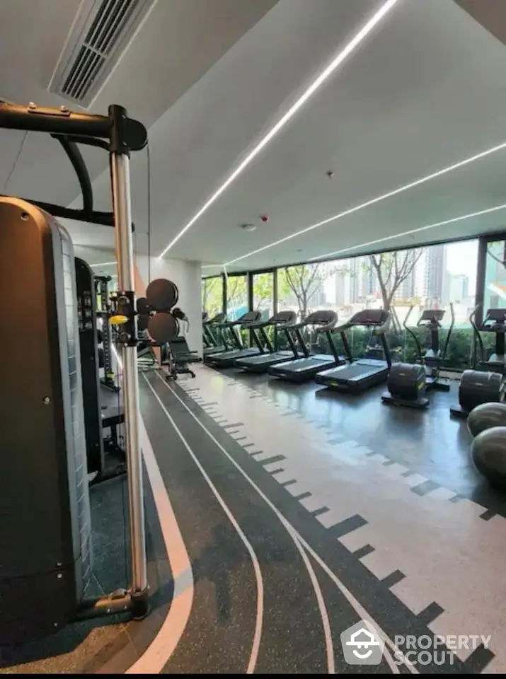 Modern gym with state-of-the-art equipment and large windows offering city views.