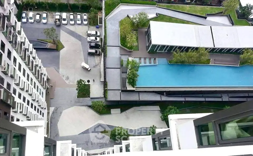 Stunning aerial view of modern apartment complex with pool and landscaped surroundings.