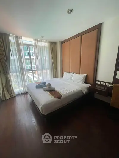 Spacious bedroom with large windows and elegant decor in modern apartment.