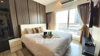 Modern bedroom with large window and stylish decor in urban apartment.