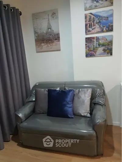 Cozy living space featuring a sleek gray sofa with plush cushions, complemented by elegant travel-themed wall art and rich, dark curtains.